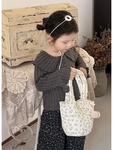 Détail du haut en maille gaufrée grise et du sac à main matelassé à fleurs pour filles