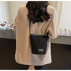 Detail of matte black suede bucket bag featuring leather trim and logo brand patch