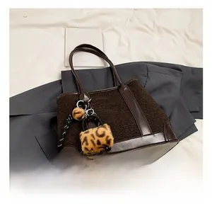 Detail of deep brown tweed tote bag with smooth faux leather trim and leopard charms