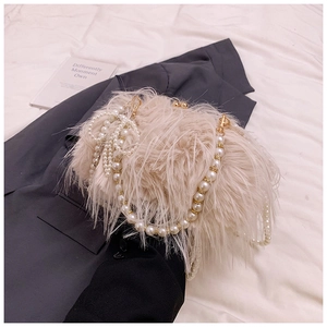 Elegant apricot plush shoulder bag with pearl tassels and straps on a grey suit blazer