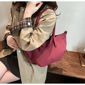 Detail of dark red tote bag with unique 3D stitching shown with an autumn coat outfit