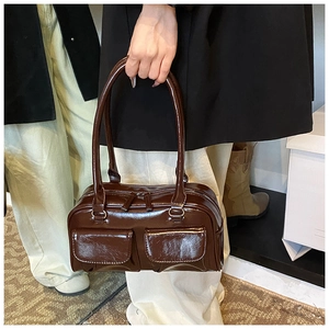 Detailed macro view of dark brown glossy leather texture and front flap pockets on the bag