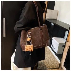 Close-up of dark brown tote bag in felt fabric with leather trim and leopard charm