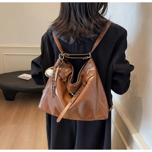 Brown leather convertible hobo bag with baseball charm shown in shoulder backpack mode