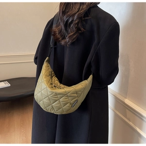 Detail of olive green quilted crescent bag with large diamond stitching and black strap