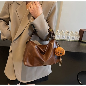 Detail of dark brown leather handbag with gold twist lock and cute plush dog charm