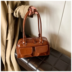 Detail of a shiny caramel brown PU leather shoulder bag on a vintage checkered bench