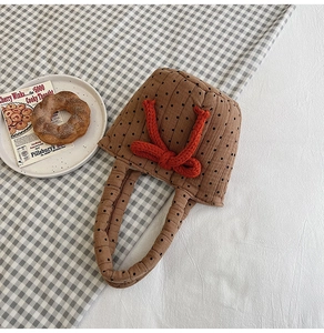 Detail of quilted brown polka dot cotton handbag with red knot decoration in a cozy setting