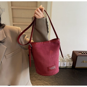 Detailed close-up of a red matte PU leather bucket bag with stitched logo and shoulder strap