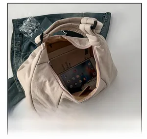 Macro view of beige crossbody dumpling bag interior showing large capacity for tablet and books