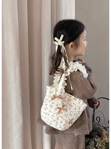 Dettaglio della borsa tote in cotone floreale con spalline in pizzo e fiocco marrone