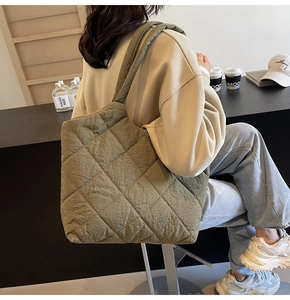 Close-up of dark green quilted tote bag featuring a diamond stitched pattern and wide strap