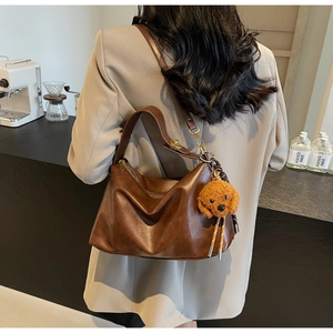 Detail of dark brown vintage PU leather hobo bag with a cute plush bear pendant