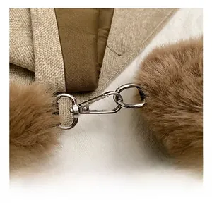 Détail du fermoir mousqueton en métal argenté avec pompon en peluche marron sur le sac