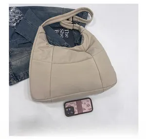 Top view of khaki quilted hobo bag with smartphone and lifestyle items for size comparison