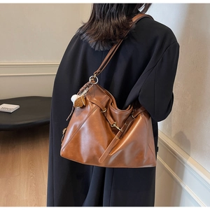 Detail of caramel PU leather tote with hardware buckle and plush white keychain