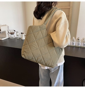 Detail of olive green quilted tote bag with diamond lattice pattern in a cafe setting