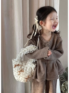 Dettaglio della borsa trapuntata a fiori per bambini con pizzo bianco e fiocchi marroni