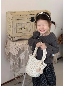 Détail d'un pull en maille automne pour enfant avec grand col et pantalon fleuri
