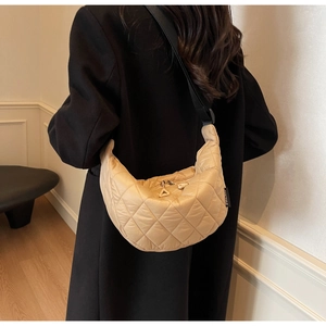 Detail of beige quilted crescent crossbody bag with black strap and metallic dual zippers
