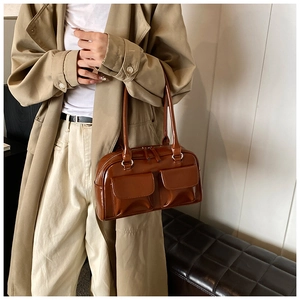 Detail view of brown glossy PU shoulder bag with symmetric flap pockets and zippers