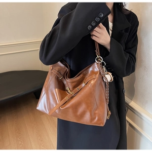 Detail of brown PU leather tote bag with sporty baseball charm and metal buckle strap