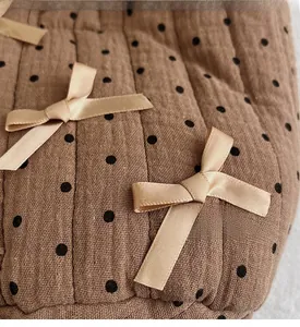 Dettaglio borsa trapuntata in cotone marrone con pois e fiocchi in raso champagne