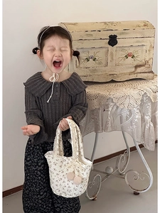 Détail d'une tenue d'automne pour fille avec haut en tricot gris et pantalon fleuri