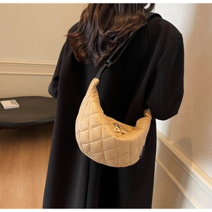 Quilted half-moon shoulder bag in beige nylon shown with an adjustable black strap on model