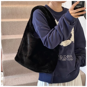 Détail de la texture douce du sac à bandoulière en fausse fourrure noire sur tenue d'automne