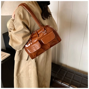 Detail view of brown patent leather shoulder bag with glossy finish and double front pockets