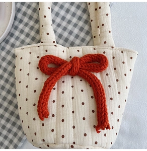 Detail of quilted cotton tote bag featuring brown polka dots and a red knitted bow