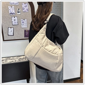 Detail view of beige crossbody bag with textured fabric and adjustable strap on model