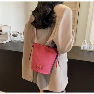 Close-up of red bucket bag with branded leather label being worn by a person