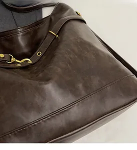 Detailed close-up of dark brown PU leather texture and gold metal hardware on women's bag