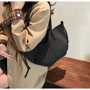 Detail view of black neoprene tote bag with knot decoration and geometric round stitching