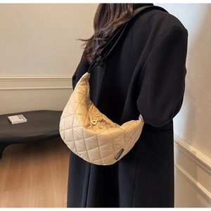 Detail of beige quilted half-moon shoulder bag featuring Vanchaon brand label on nylon