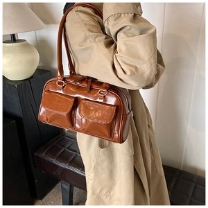 Brown vintage PU leather shoulder bag with dual front pockets worn by a model in a trendy style