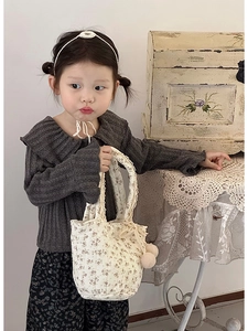 Détail du sac en coton floral avec dentelle et pompons en peluche sur une tenue vintage