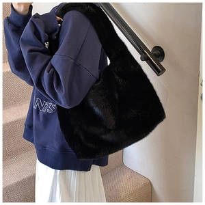 Détail de la texture en fausse fourrure noire sur un grand sac à bandoulière épuré