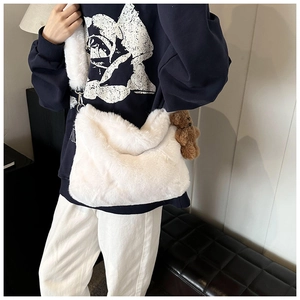 Détail d'un sac à bandoulière en peluche blanche avec un adorable porte-clé ours brun