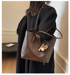 Détail d'un grand sac cabas en cuir marron café avec charm de baseball et bandoulières