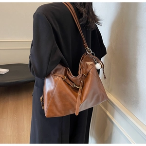 Detail of brown PU leather hobo bag with metal buckle and creative baseball charm strap