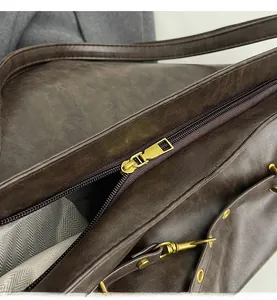 Detail of golden zipper and herringbone fabric lining on dark brown vintage PU leather bag