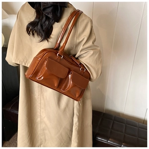 Caramel glossy shoulder bag with dual front pockets worn over a beige trench coat