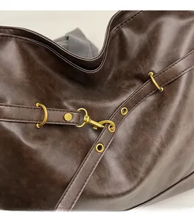 Detail of dark brown vintage PU leather texture and antique bronze hardware on the bag