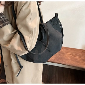 Detail view of a large black PU tote bag styled with a khaki trench coat for autumn fashion