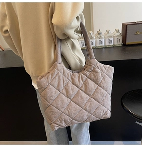 Detail of taupe quilted tote bag featuring a diamond pattern and long shoulder straps