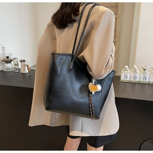 Détail du sac cabas en similicuir noir avec pendentif sport dans un décor de café chic