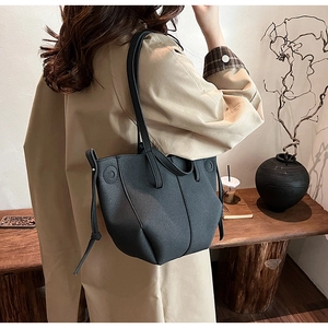 Detailed back view of a black grainy PU leather tote bag worn by a model in a warm interior